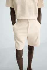 Bermuda azul marino de corte regular fit, confeccionada en tejido de algodón y lino. Cuenta con bolsillos frontales y traseros, cierre frontal con cremallera y botón.