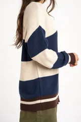 Sweater oversize de tejido de punto con diseño de rayas horizontales anchas en color beige y azul marino, cuello redondo marrón y puños y dobladillo en marrón con líneas beige y blancas.