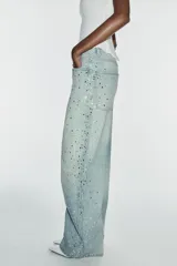 Jeans baggy de tiro medio, pierna ancha y diseño de cinco bolsillos, confeccionados en denim celeste con aplicaciones de brillos en los laterales.