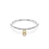 Brazalete rígido de la colección Idyllia, con diseño de media caña adornado con cristales transparentes. Presenta un dije central en forma de corazón tipo medallón, con baño en tono oro y una zirconia rosa en una cara, y pavé de cristales con baño de rodio en la otra.