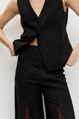Pantalón sastrero de corte ancho y tiro alto, color negro con inserciones laterales en tono marrón que forman godets.