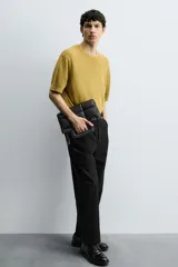 Bolso tipo shopper de diseño acolchado con patrón de cuadros, confeccionado en material sintético negro. Presenta asas de mano integradas en la estructura superior y un detalle de borla colgante con herraje metálico.