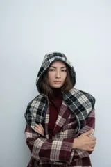 Bufanda con capucha integrada, confeccionada en tejido de lana a cuadros en tonos bordó, negro y beige, con bordes terminados en cuero sintético negro.