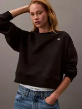 Buzo negro de cuello redondo, confeccionado en tejido fleece de mezcla de algodón y poliéster. Presenta el logo de archivo de Calvin Klein bordado en blanco en el frontal.