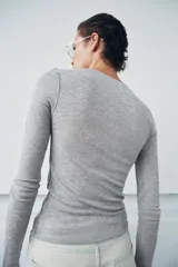 Top de punto fino y semitransparente color gris claro, con cuello redondo y manga larga.