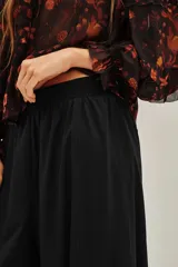 Pantalón tipo babucha de corte holgado y tiro alto, con cintura elástica y diseño de pierna amplia que se estrecha hacia los tobillos.