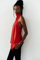 Top halter asimétrico de color rojo, confeccionado en tejido elástico, con cuello alto y cierre posterior con botones.