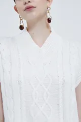 Chaleco tejido color marfil con cuello en V, sin mangas y tajos laterales.