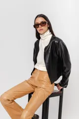 Chaqueta de cuero negra entallada, de largo a la cintura y acabado rústico. Sin forro.