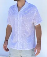 Camisa blanca de broderie con cuello cubano y mangas cortas. Diseño con calados florales. Cierre frontal con botones.