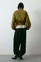 Campera bomber de tejido grueso color verde militar, con cuello corto acanalado, cierre frontal y bolsillos insertados. Cuenta con hombros caídos, mangas abullonadas y puños y bajo acanalados.