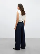 Pantalón de denim azul oscuro, de pierna ancha, con cierre de botón y cremallera, bolsillos laterales oblicuos, bolsillos parche traseros, pespuntes a contraste, cinturilla interior de sastrería, ceñidor y goma para dos posiciones, y bajo con goma y ceñidor.