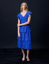 Vestido blanco de gasa con capas, marca Julia Jordan. Escote en V, manga corta con volados, corte en cintura y abertura central en espalda con cierre invisible.