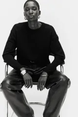 Buzo negro de tejido suave con lana, cuello redondo acanalado, hombros caídos y mangas largas. Puños y bajo en punto acanalado.