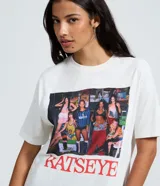 Remera blanca de algodón con cuello redondo y mangas cortas. Presenta un estampado fotográfico frontal de la banda Katseye con el nombre del grupo impreso en letras rojas en la parte inferior.