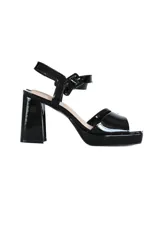 Sandalia de tacón alto con plataforma, confeccionada en cuero charolado color negro. Presenta un diseño de tira ancha en el empeine y pulsera ajustable al tobillo con hebilla metálica. Cuenta con un tacón cuadrado robusto y suela con plataforma integrada.
