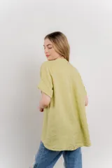 Blusa blanca de lino con escote en V abotonado y mangas cortas arremangadas.