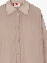Camisa extra larga y oversize de lyocell color negro, con textura arrugada, cuello camisero y mangas largas con puños de satén.