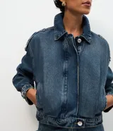 Campera bomber de jean azul oscuro, de corte corto con mangas globo, cuello con solapa y cierre frontal abotonado.