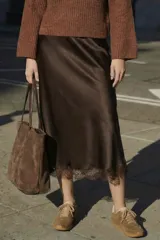 Falda midi de satén color marrón oscuro, corte al bies, con detalle de encaje en el ruedo.