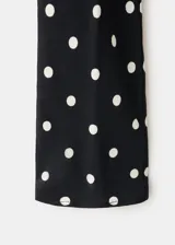 Vestido largo negro con estampado de lunares blancos, de corte recto, escote redondo y mangas largas.
