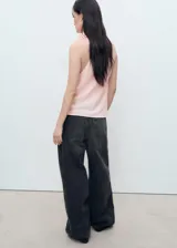 Blusa sin mangas color rosado, con cuello drapeado y detalle de flor aplicada en el cuello. Presenta un diseño recto y holgado.