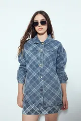 Sobrecamisa de jean con estampado de cuadros, corte relajado, cuello clásico y cierre frontal con botones metálicos.