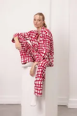 Conjunto de pijama de dos piezas con estampado de cuadros irregulares en rojo y blanco. Incluye una camisa de manga larga con cuello y botones frontales, y un pantalón largo a juego.