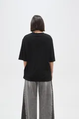 Remera de corte holgado, color negro, con cuello redondo y mangas cortas.