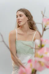 Pijama de dos piezas, compuesto por una musculosa blanca con detalle de puntilla negra elástica en el escote y un short blanco con elástico y lazo negro en la cintura.