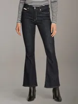 Pantalón de jean azul oscuro, de corte ajustado en la cadera y muslos, y acampanado a partir de la rodilla.