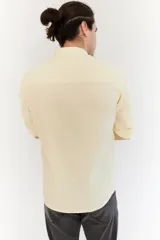 Camisa color amarillo claro, de corte clásico, con cuello mao y mangas largas con puños abotonados.