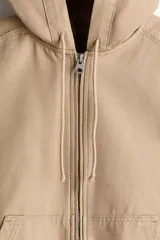 Campera tipo worker de algodón con cierre frontal, capucha con cordón ajustable, bolsillos delanteros abiertos y puños y bajo con elástico.