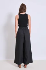Pantalón negro de tiro alto y corte palazzo, con detalle de strass plateado en forma de ondas verticales.
