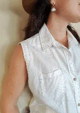 Musculosa tipo camisa con cuello camisero, cierre frontal de botones y dos bolsillos delanteros en el pecho. Diseño a rayas verticales en tonos celeste y blanco.