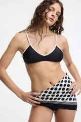 Top de bikini negro con borde blanco y tirantes finos blancos.