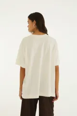 Remera blanca de algodón, de corte oversize y manga corta, con estampa frontal inspirada en la Floresta da Tijuca que incluye ilustraciones de un loro y un mirador.
