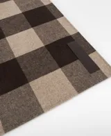 Bufanda de lana merino, viscosa y poliéster, con diseño a cuadros grandes en tonos marrón oscuro y beige. Presenta un cierre de botón y una etiqueta exterior logotipada.