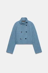 Chaqueta corta de cuello subido y manga larga, con diseño de cuadros en tonos azules. Presenta cierre frontal cruzado con botones oscuros y bolsillos de vivo en el delantero.