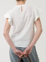 Blusa de manga corta color blanco, con cuello redondo y detalles de crochet en las mangas. Presenta un cierre de botón en la parte posterior del cuello.