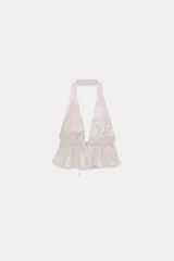 Top crop blanco con acabado foil brillante, cuello halter y escote pronunciado en pico. Presenta frunces en el bajo y un cordón ajustable en el centro inferior.
