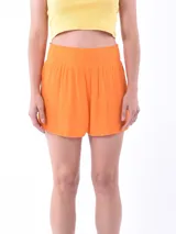 Short de tela liviana con textura plisada, color naranja, con cintura elástica alta tipo nido de abeja.