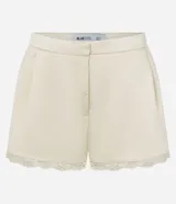 Minishort satinado de tiro medio color beige, con pinzas delanteras, bolsillos y detalle de encaje en el ruedo.