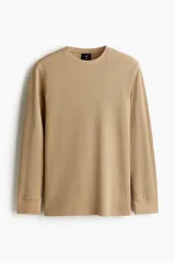 Remera de manga larga en punto waffle color beige, con cuello redondo y ribete acanalado en cuello y puños. Presenta un corte ajustado que realza la silueta.