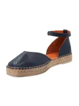 Alpargatas de cuero color azul marino, con suela revestida en yute trenzado, puntera redonda y tira ajustable al tobillo con hebilla metálica.