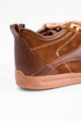 Championes urbanos de cuero vacuno en color marrón, con diseño de paneles superpuestos y costuras decorativas en zigzag. Presenta cordones bicolores y suela de goma al tono.