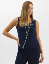 Conjunto de tres piezas compuesto por una musculosa de silueta recta, un pantalón de seda fría con caída fluida y cintura elastizada, y un kimono de tul con bordado floral, frente abierto y mangas acampanadas. Incluye collar largo removible.