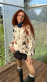 Buzo tejido de punto color crudo, con diseño oversized y cuello redondo. Presenta un bordado artesanal de insectos y mariposas en diversos colores distribuidos por toda la prenda. Cuenta con puños y ruedo acanalados con detalles de costuras en contraste.