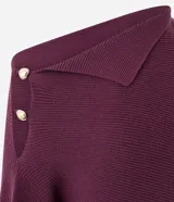 Suéter de tricot color bordó, con textura acanalada, corte recto y caída suelta. Presenta diseño de hombro caído, manga larga, cuello asimétrico con solapa estructurada y detalle de botones decorativos en el hombro.