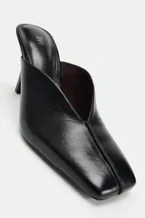 Zapato mule de tacón alto fino color negro en piel, con escote en pico, costura central delantera y punta cuadrada.